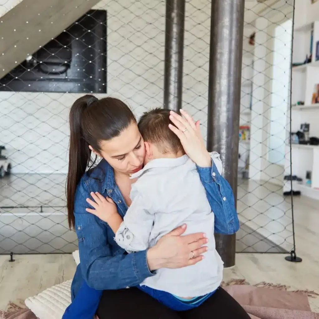 Mãe acolhendo o filho no colo em casa, cena do dia a dia de uma família atípica